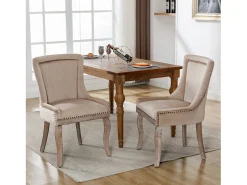 Conjunto de 2 sillas de terciopelo beige con patas de madera curvadas y remaches dorados.