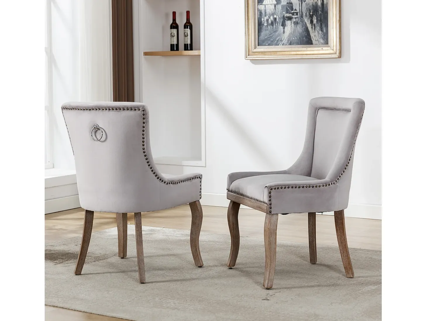 Juego de 2 sillas de terciopelo gris con patas de madera curvadas y remaches dorados.