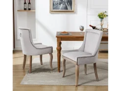 Juego de 2 sillas de terciopelo gris con patas de madera curvadas y remaches dorados.