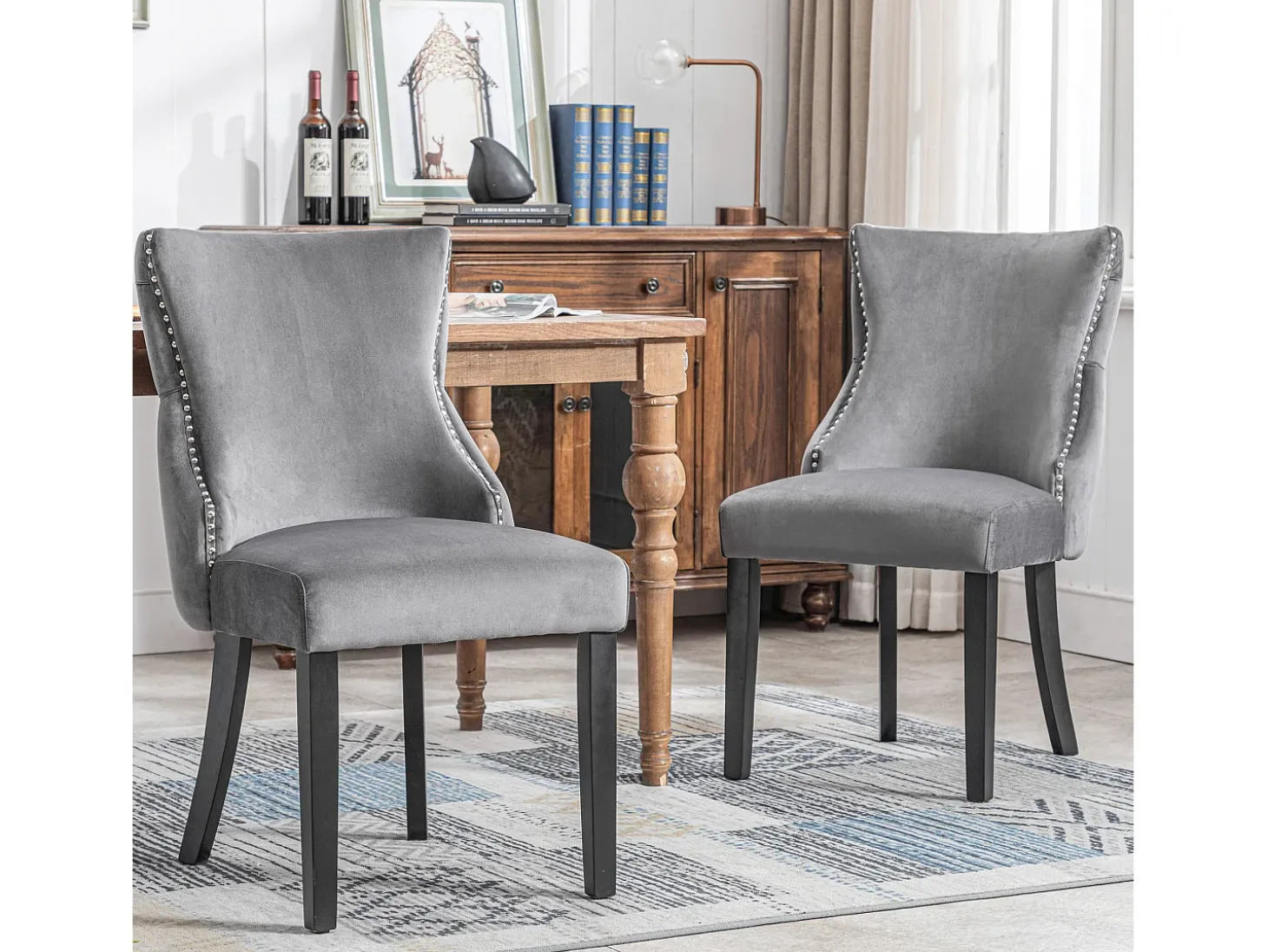 Juego de 2 sillas de terciopelo gris con patas de madera gris, botones decorativos y remaches plateados.